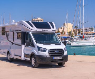 Autocaravana aparcada junto al puerto deportivo con embarcaciones