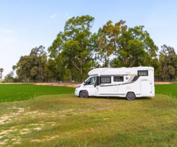Autocaravana blanca estacionada bajo árboles en paisaje natural en Serra de Mariola
